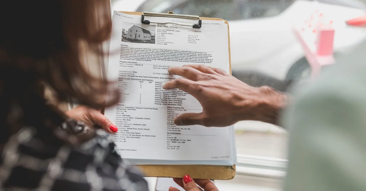 Agent immobilier discutant des détails de la propriété avec un client utilisant un carnet de notes à l'intérieur.