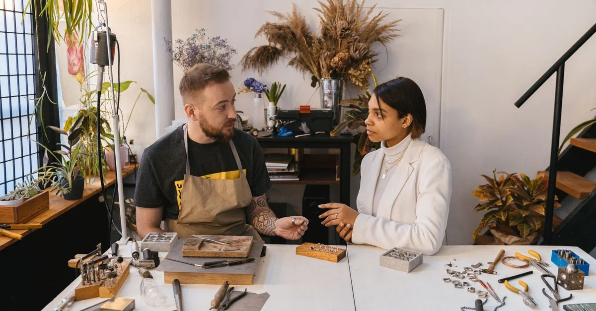 Homme et femme discutant du design de bijoux dans un atelier artisanal.